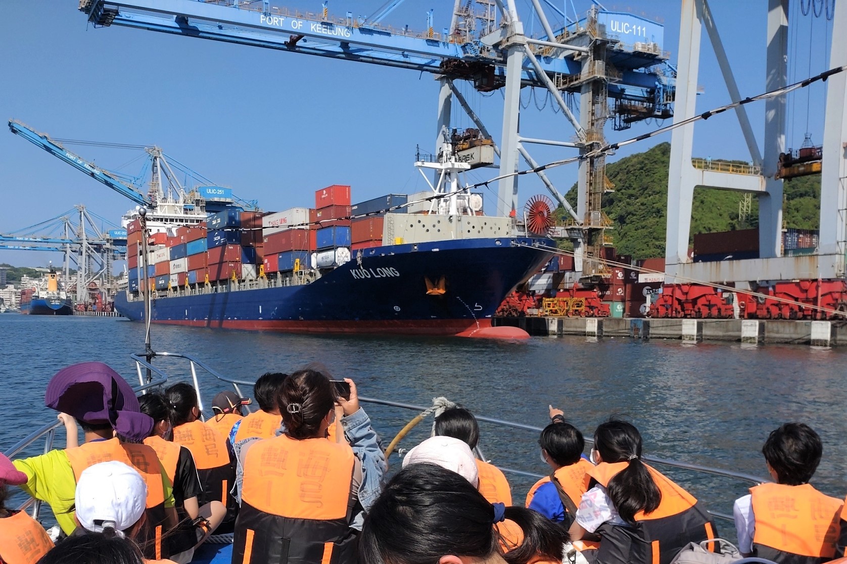 學生於船上近距離看見停靠在基隆港邊的商船裝卸貨物
